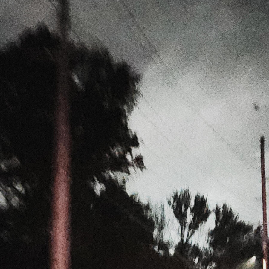 A dark, blurry picture taken while driving through a Midwestern neighborhood, the sky glowing in a white light.